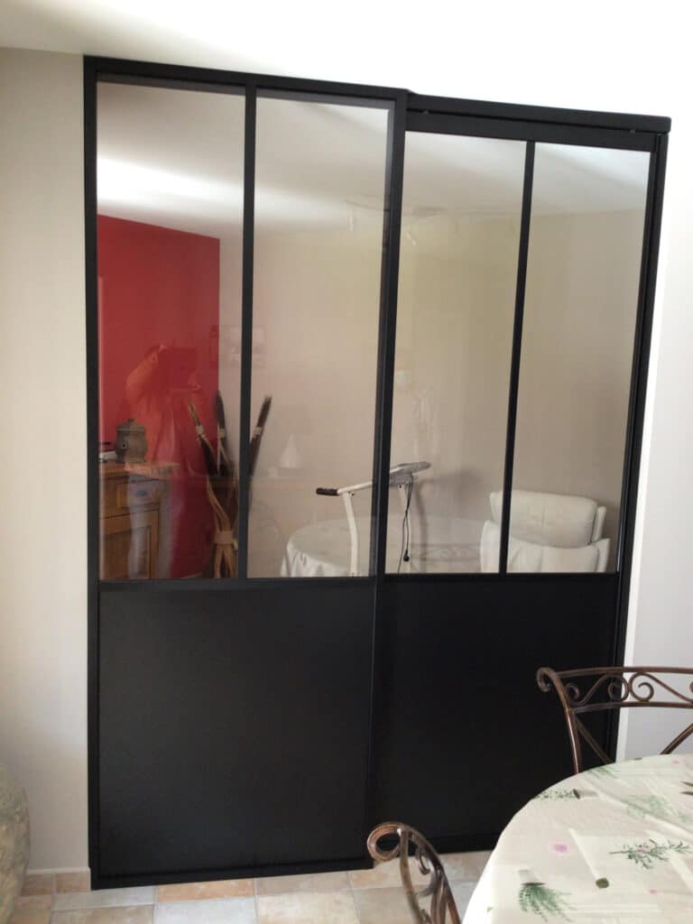 Verrière coulissante noire style industriel avec vitres transparentes pour une séparation de pièce élégante.
